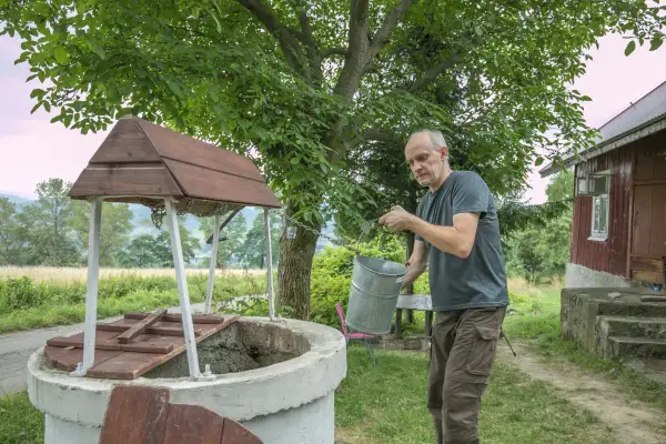 Mężczyzna czerpie wodę z **studni głębinowej**. Posiadanie takiej studni wymaga odpowiedniego **pozwolenia**.
